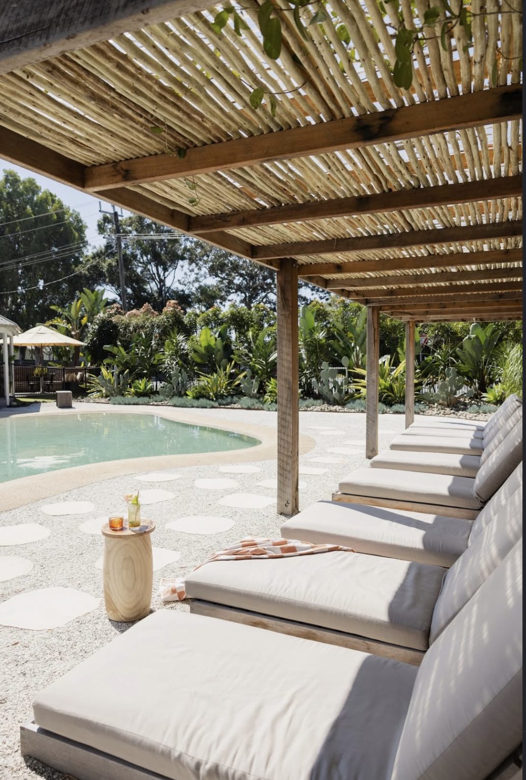 Las reposeras bajo la pérgola de troncos, con los tragos servidos junto al agua