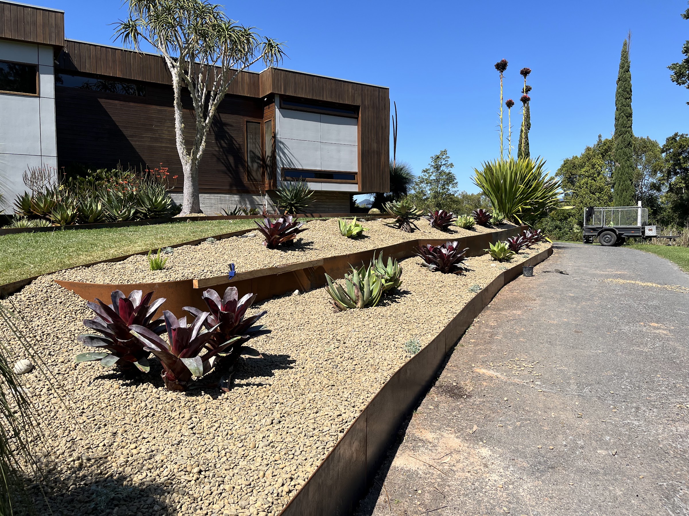 Jardín en terrazas con borde de acero corten y plantación de agaves y bromelias, Tweed Valley
