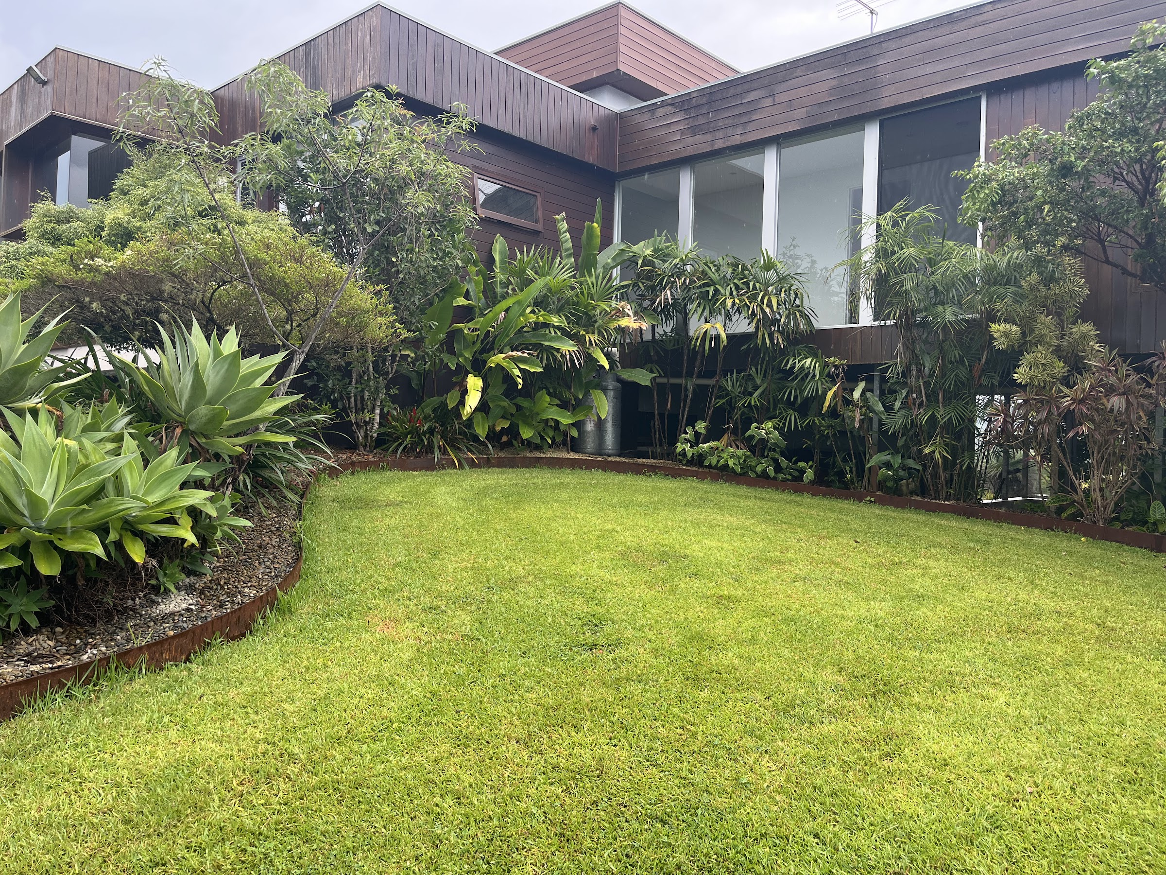 Jardín tropical en la parte trasera de la casa, con agaves y palmeras