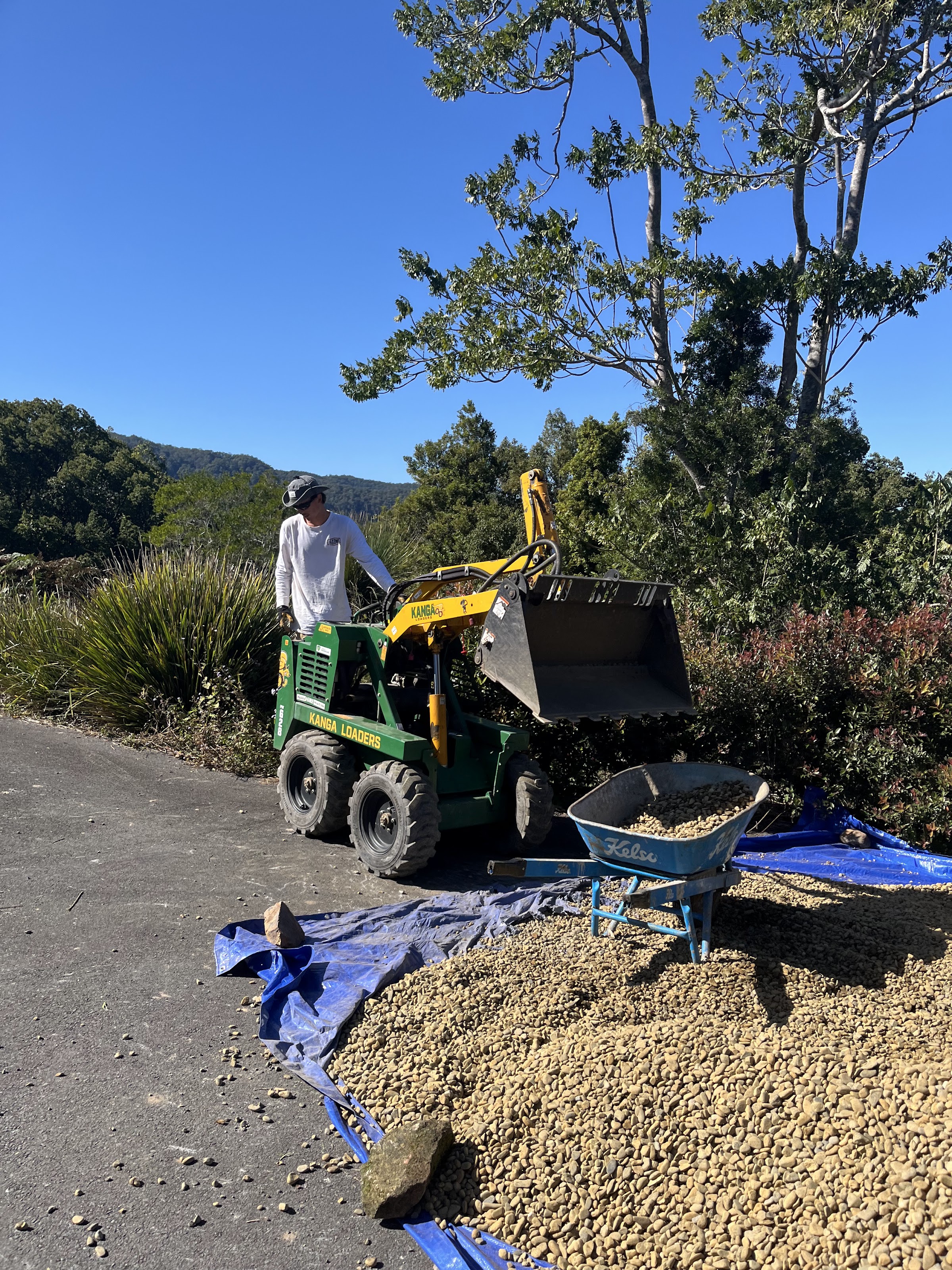 Obra en proceso: miniexcavadora cargando piedra recolectada en el sitio
