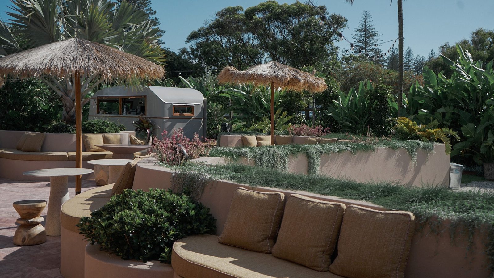 El lounge exterior con sombrillas de paja y el food truck vintage