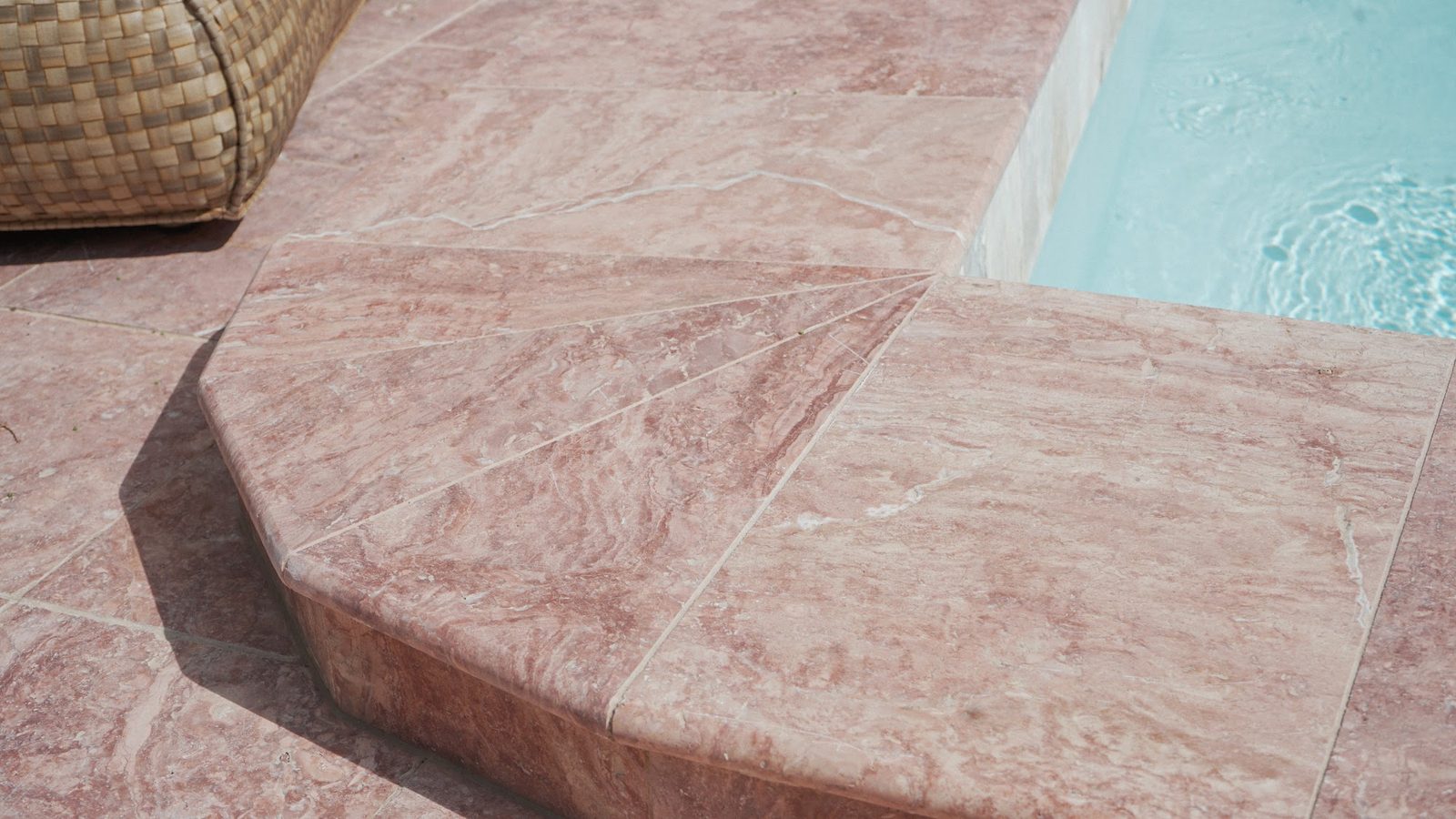 Detalle del borde de piedra rosada de la piscina