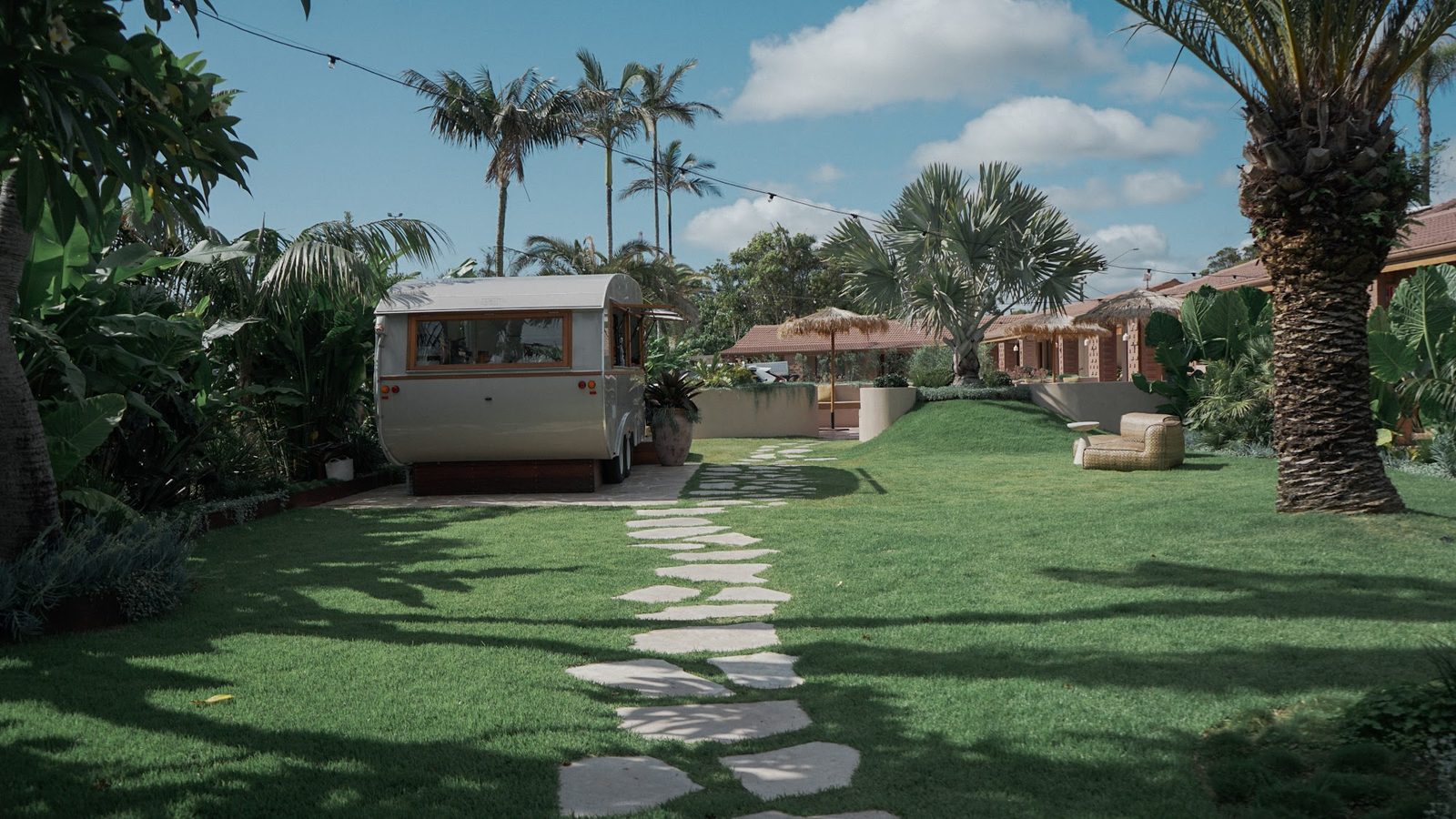 La casita trailer sobre el césped, con sendero de piedra