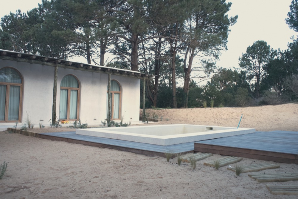 Casa ZN — deck y piscina entre pinos, costa uruguaya